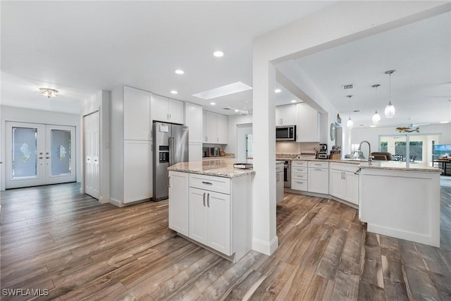 kitchen featuring white cabinets, pendant lighting, kitchen peninsula, and appliances with stainless steel finishes