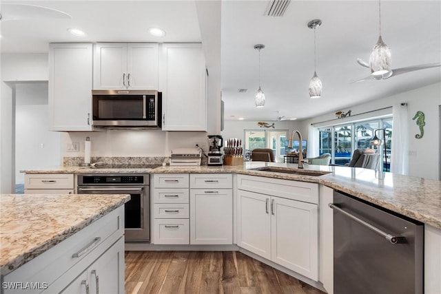 kitchen featuring white cabinetry, sink, decorative light fixtures, and appliances with stainless steel finishes