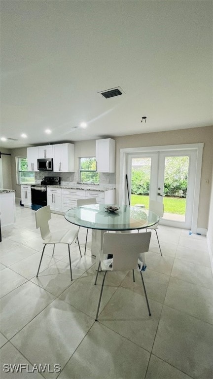 dining space with light tile patterned flooring, french doors, and plenty of natural light