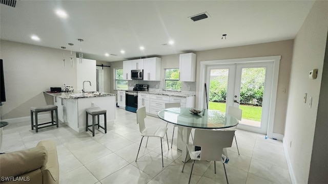 dining space featuring light tile patterned floors, a wealth of natural light, sink, and french doors