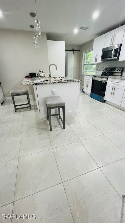 kitchen with white cabinetry, a barn door, pendant lighting, light tile patterned floors, and stainless steel appliances