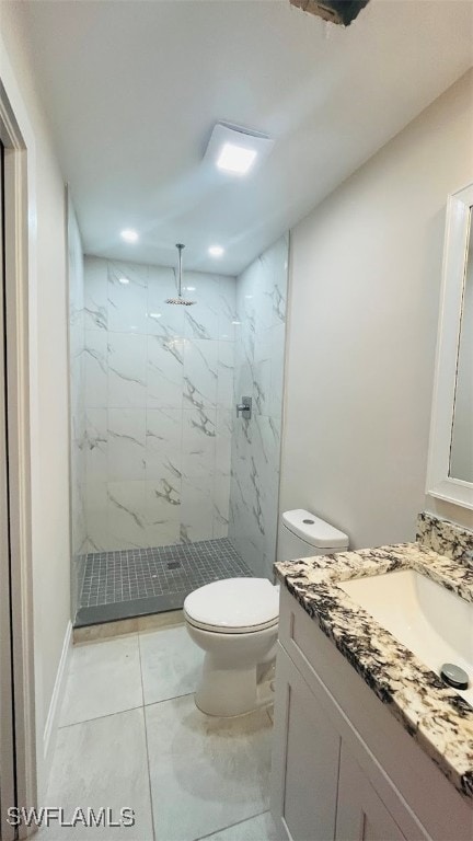 bathroom with tile patterned flooring, vanity, toilet, and tiled shower