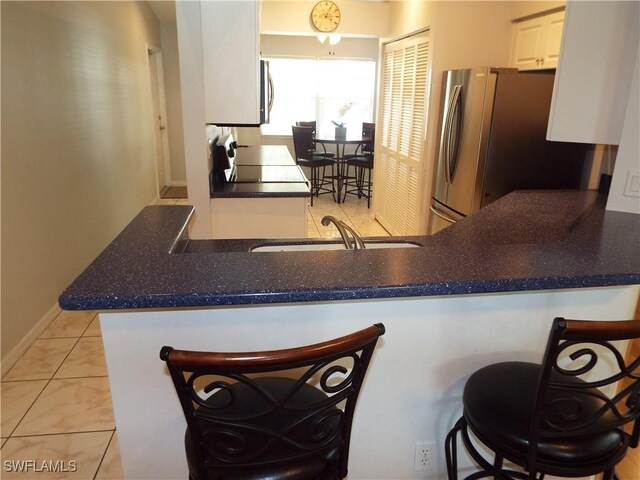 kitchen featuring sink, a breakfast bar area, stainless steel appliances, white cabinets, and kitchen peninsula