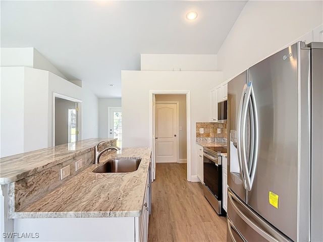 kitchen with appliances with stainless steel finishes, light stone counters, white cabinets, light hardwood / wood-style flooring, and sink