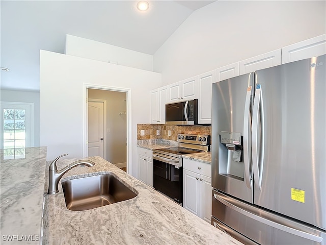 kitchen featuring tasteful backsplash, appliances with stainless steel finishes, white cabinetry, sink, and vaulted ceiling