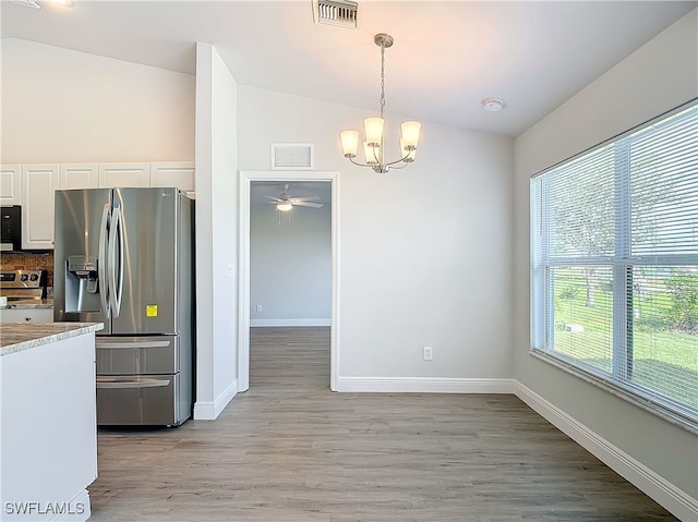 kitchen featuring tasteful backsplash, stainless steel appliances, light hardwood / wood-style floors, white cabinetry, and vaulted ceiling