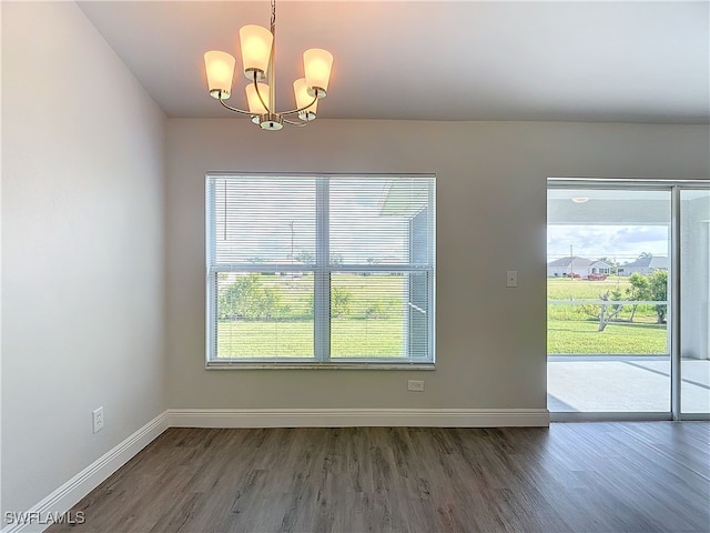 spare room featuring an inviting chandelier and hardwood / wood-style flooring