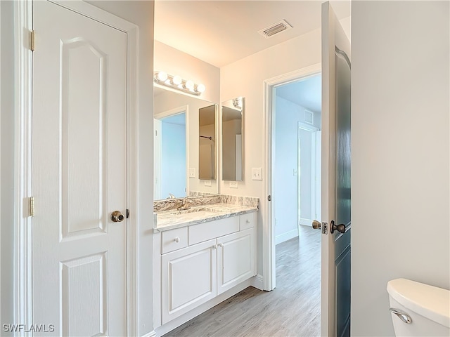 bathroom featuring vanity, toilet, and hardwood / wood-style floors