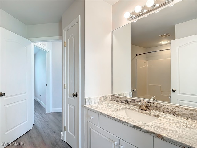 bathroom with hardwood / wood-style flooring, vanity, and shower / tub combination