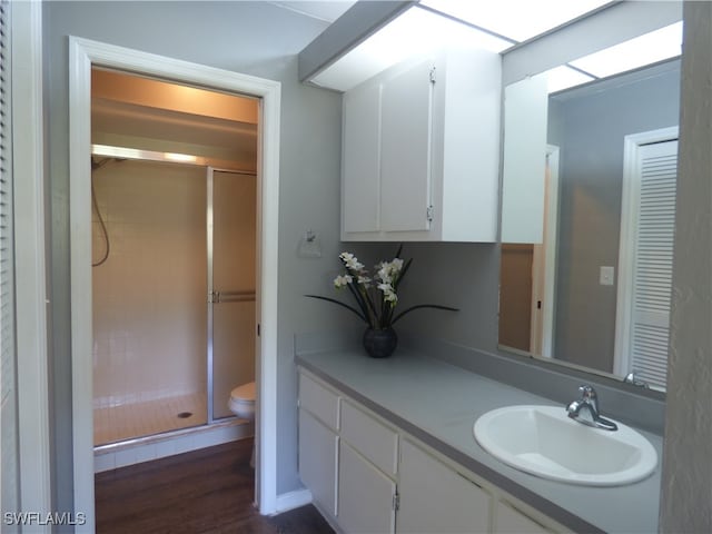 bathroom with a shower with shower door, toilet, vanity, and wood-type flooring