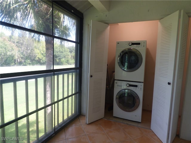 laundry area with light tile patterned flooring, stacked washing maching and dryer, and a healthy amount of sunlight