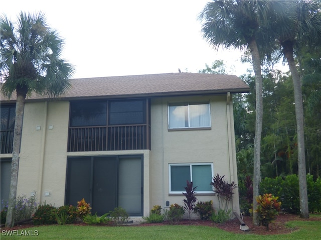 rear view of property featuring a lawn and a balcony