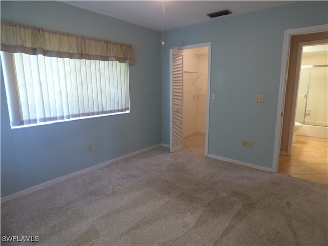 unfurnished bedroom with carpet floors, a spacious closet, connected bathroom, and a closet