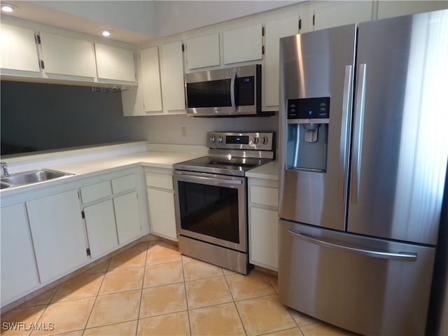 kitchen featuring white cabinets, sink, light tile patterned floors, and stainless steel appliances