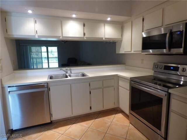 kitchen featuring sink, stainless steel appliances, light tile patterned flooring, and white cabinets