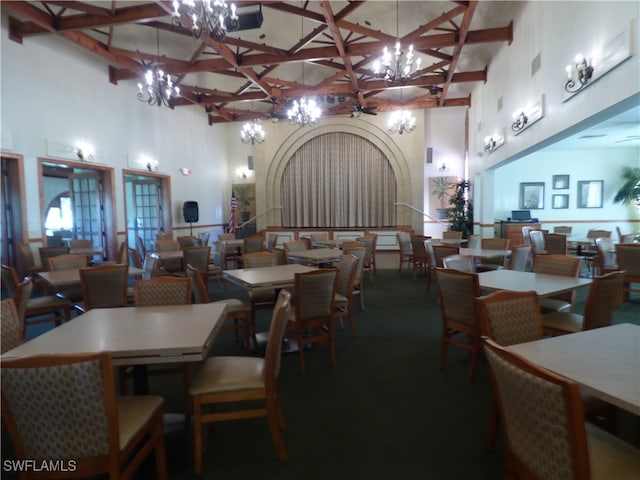 dining area featuring an inviting chandelier, beamed ceiling, and a towering ceiling