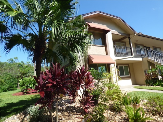 view of home's exterior featuring a balcony and a lawn