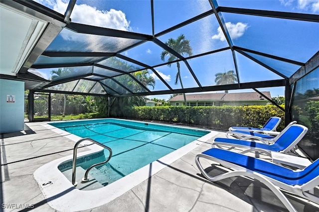 view of pool with glass enclosure and a patio