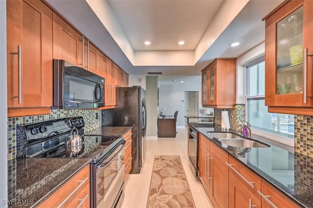 kitchen featuring a raised ceiling, light tile patterned floors, backsplash, black appliances, and sink