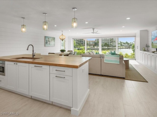 kitchen with wood counters, white cabinetry, plenty of natural light, and sink