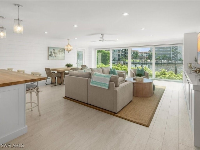 living room featuring ceiling fan, light hardwood / wood-style flooring, and a water view