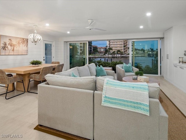 living room featuring light hardwood / wood-style flooring and ceiling fan with notable chandelier