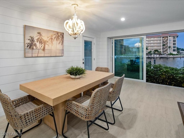 dining space with wooden walls, an inviting chandelier, and light wood-type flooring