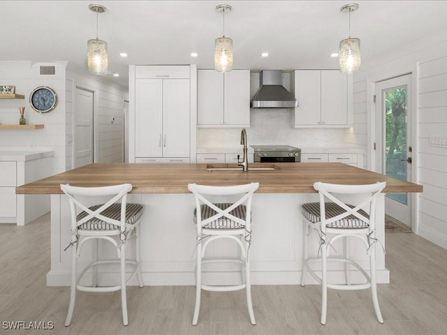 kitchen featuring white cabinets, sink, wall chimney exhaust hood, and pendant lighting