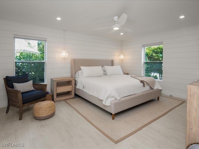 bedroom with ceiling fan, hardwood / wood-style floors, and wooden walls