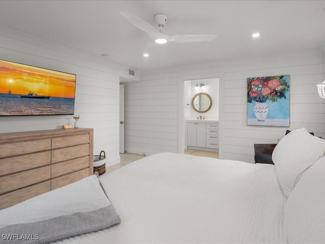 bedroom featuring connected bathroom, ceiling fan, and wood walls