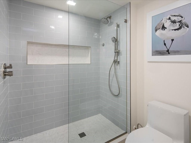 bathroom with a tile shower and toilet