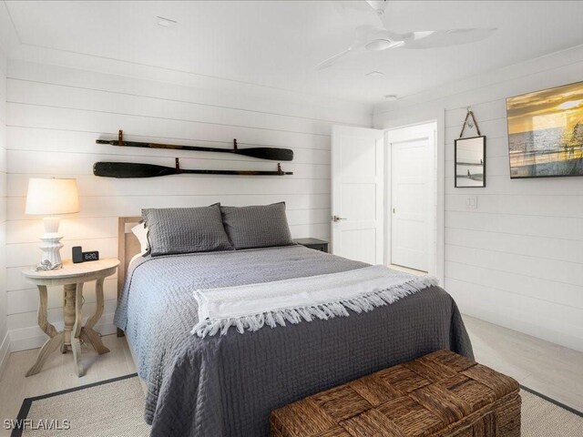 bedroom with ceiling fan and wood walls