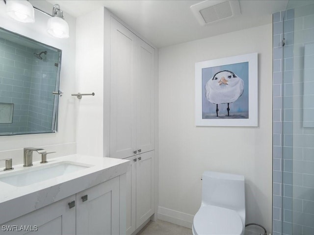 bathroom featuring vanity, toilet, and a tile shower