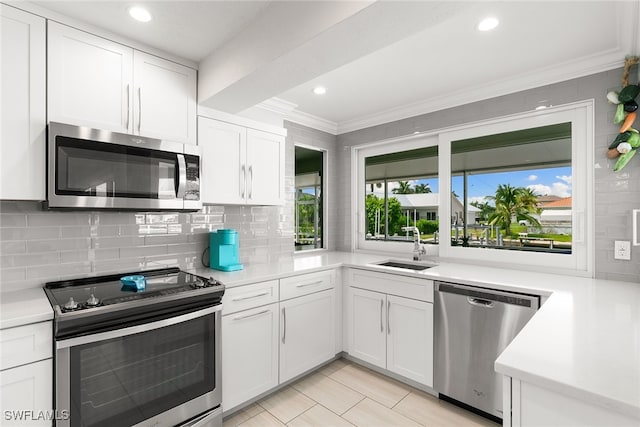 kitchen with appliances with stainless steel finishes, ornamental molding, and white cabinetry