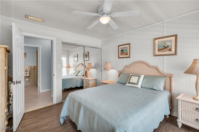 bedroom featuring ceiling fan, dark wood-type flooring, a closet, and a textured ceiling