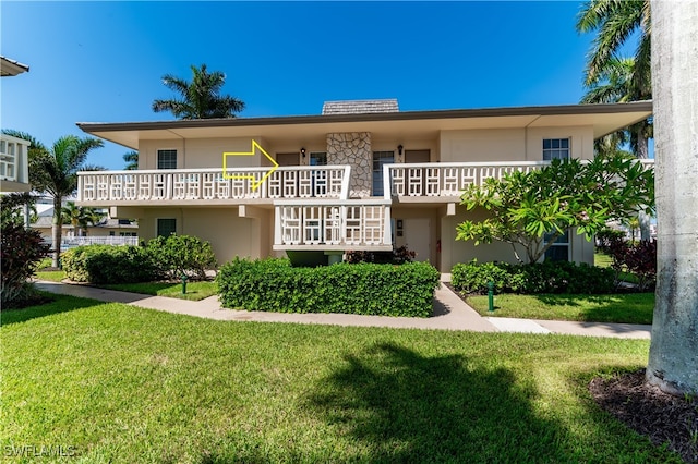 view of front of home featuring a balcony and a front yard