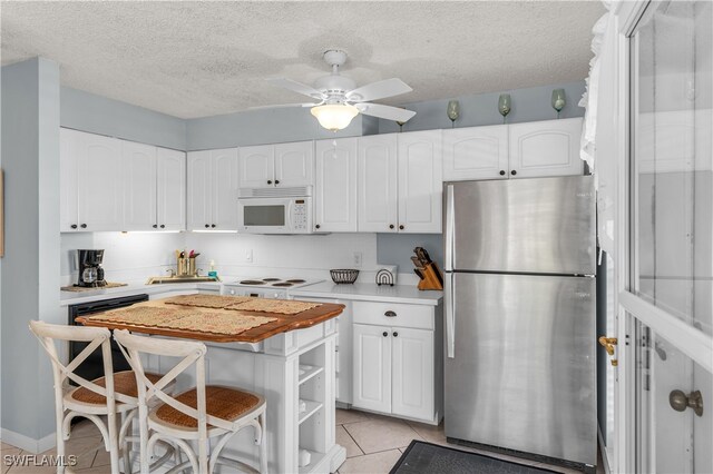 kitchen featuring ceiling fan, white cabinetry, and stainless steel refrigerator