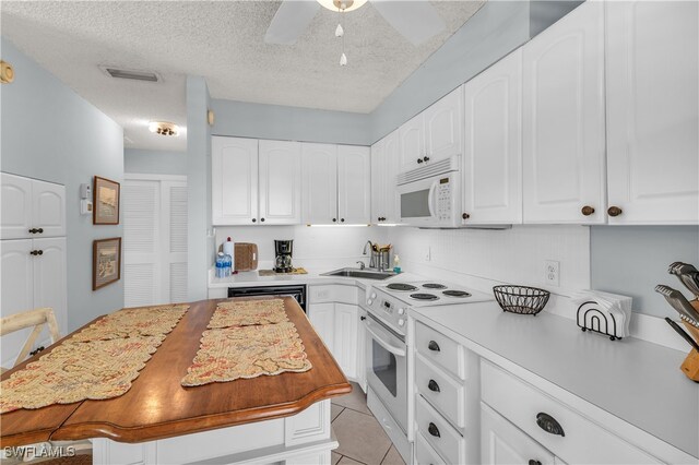 kitchen featuring white cabinetry, a textured ceiling, and white appliances