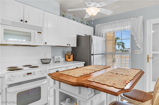 kitchen featuring backsplash, a textured ceiling, white appliances, and white cabinetry