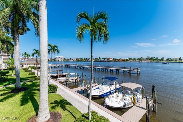 view of dock with a lawn and a water view