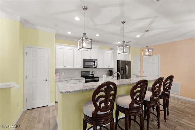 kitchen with appliances with stainless steel finishes, decorative light fixtures, light hardwood / wood-style floors, and light stone countertops