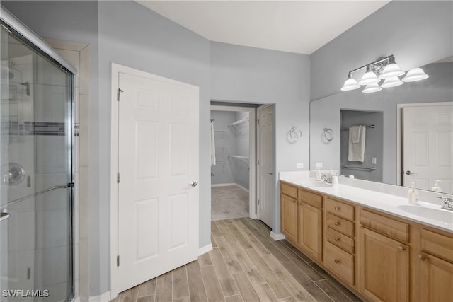 bathroom with a shower with door, hardwood / wood-style flooring, and dual bowl vanity