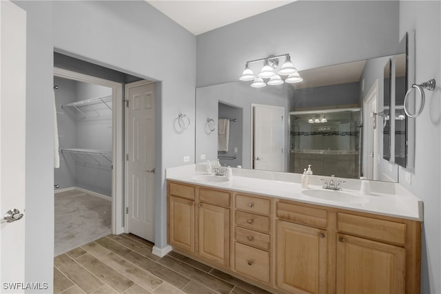 bathroom with wood-type flooring, a shower with door, and dual bowl vanity