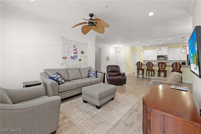 living room featuring ceiling fan, crown molding, and light hardwood / wood-style flooring