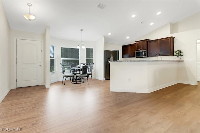 kitchen featuring black fridge with ice dispenser, decorative light fixtures, vaulted ceiling, kitchen peninsula, and light hardwood / wood-style floors