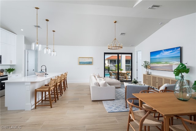 living room with light wood-type flooring, lofted ceiling, and sink