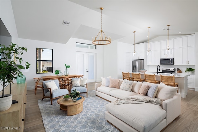 living room featuring wood-type flooring, lofted ceiling, and a chandelier