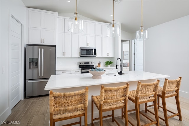 kitchen with light wood-type flooring, sink, an island with sink, lofted ceiling, and stainless steel appliances