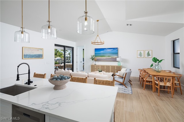 kitchen featuring vaulted ceiling, dishwasher, light wood-type flooring, decorative light fixtures, and sink