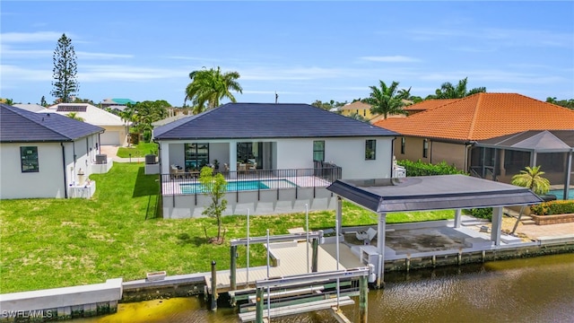 back of house featuring a lawn, a water view, and a patio area